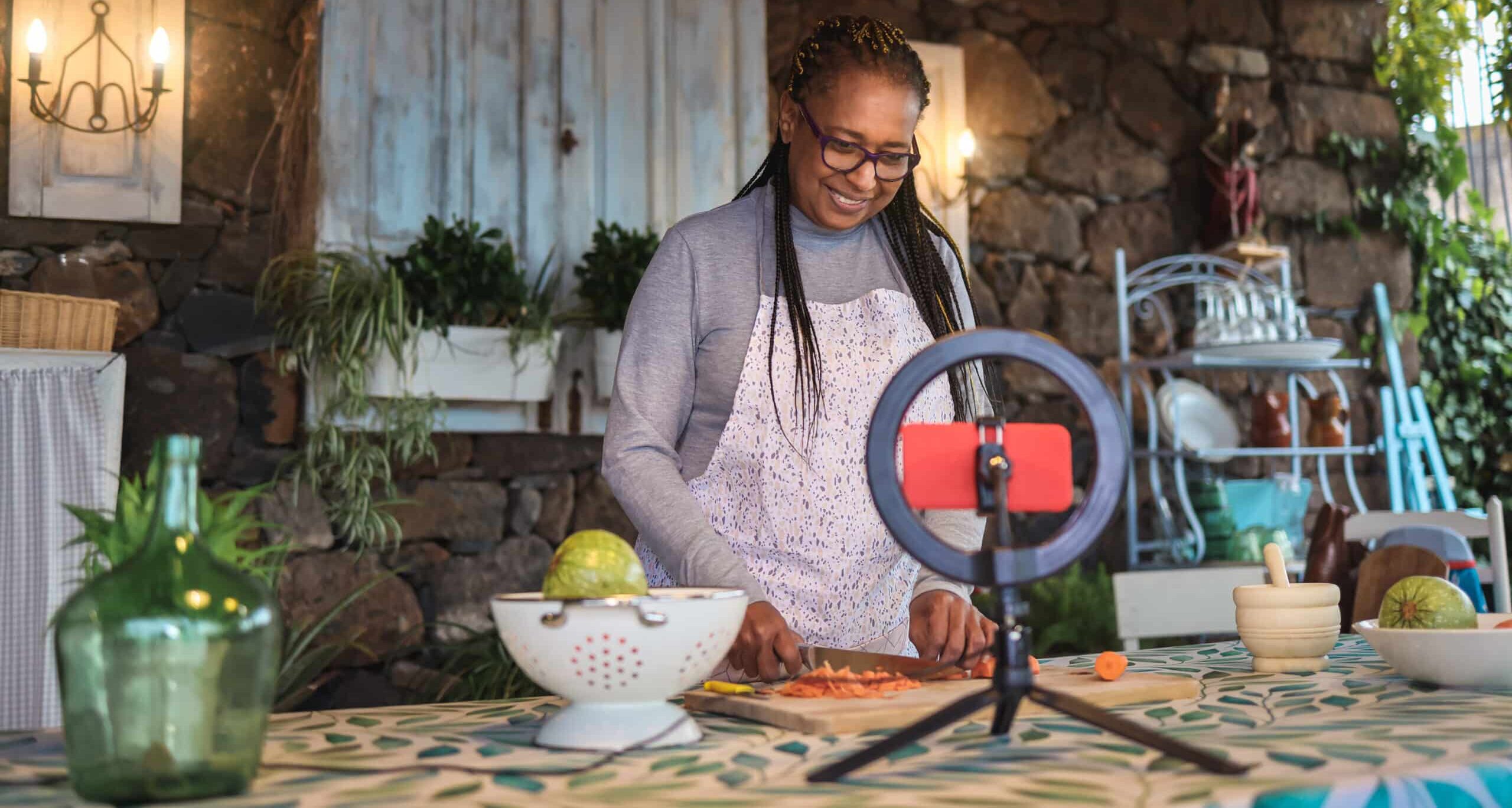 African senior woman streaming online virtual masterclass cooking lesson outdoors at home