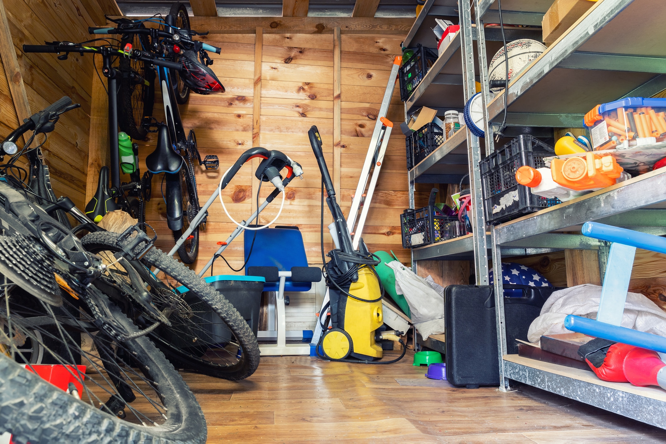 Craigslist for sale. Suburban home wooden storage utility unit shed with miscellaneous stuff on shelves, bikes, exercise machine, ladder, garden tools and equipment. Messy and chaos at house yard barn. Organization order.
