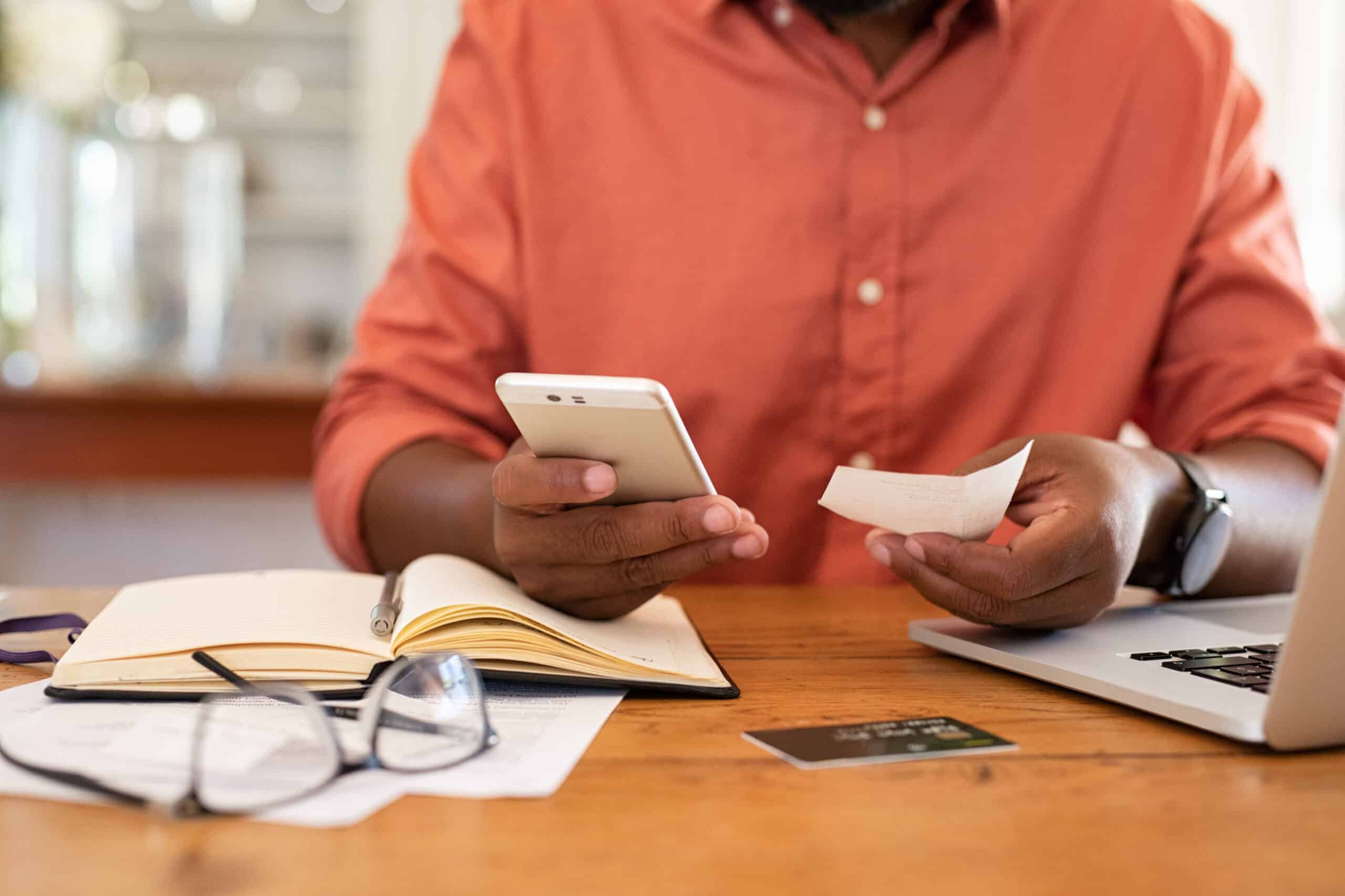 Man on phone with papers and credit card on table