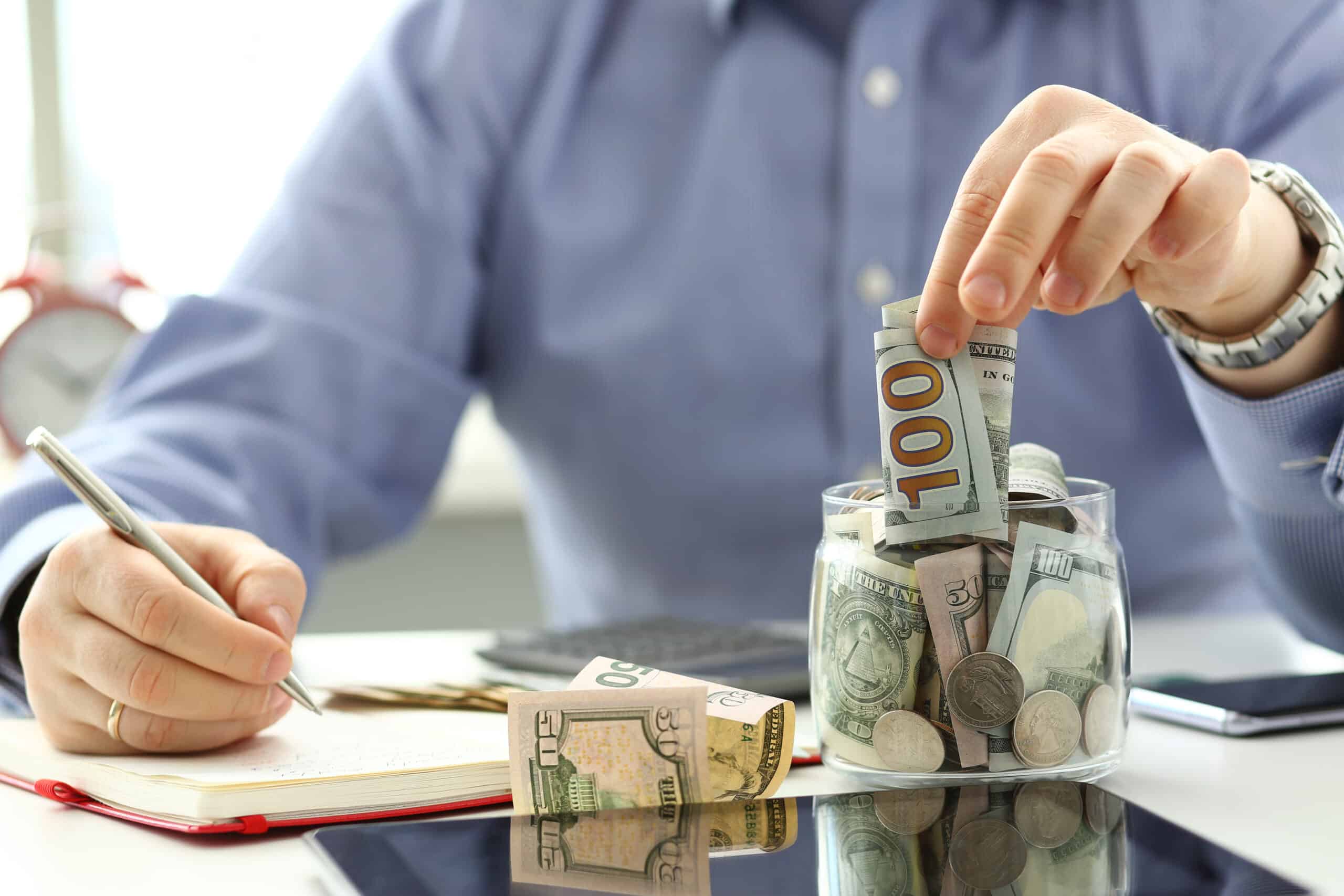 Man putting money into a jar of an emergency fund.