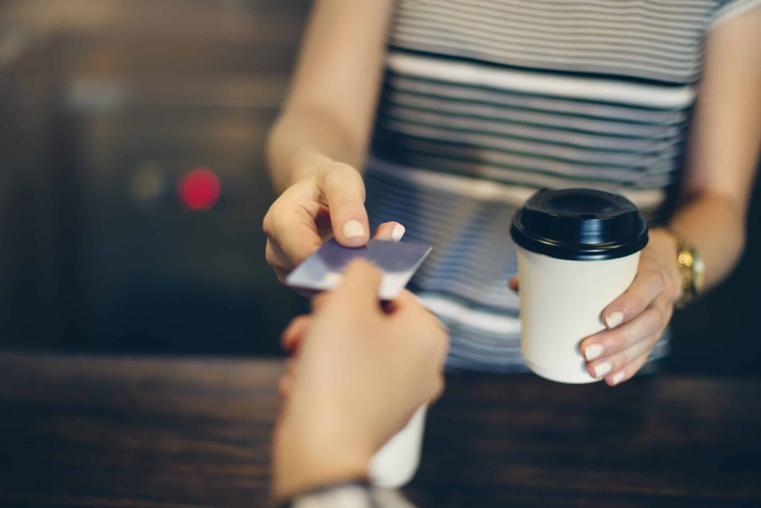 Woman paying for coffee with a card. Budget challenge article.